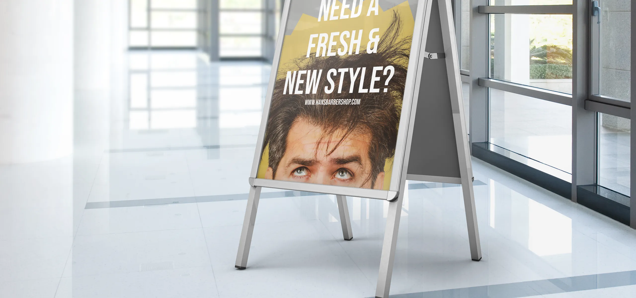 Reklamní áčko s plakátem umístěné v interiéru u oken
